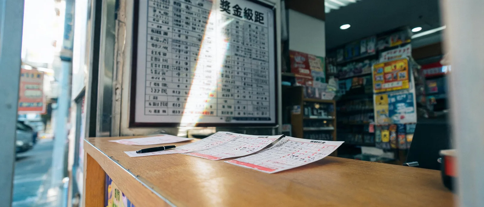 彩券行櫃檯上的選號單與後方牆面獎金表看板,示意賓果賓果的獎金級距對照