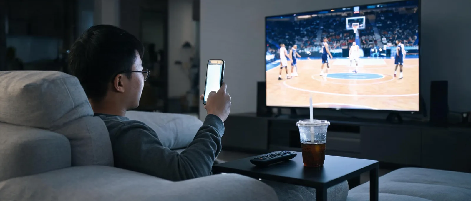 球迷用手機即時追蹤NBA比分,搭配電視轉播畫面交叉確認